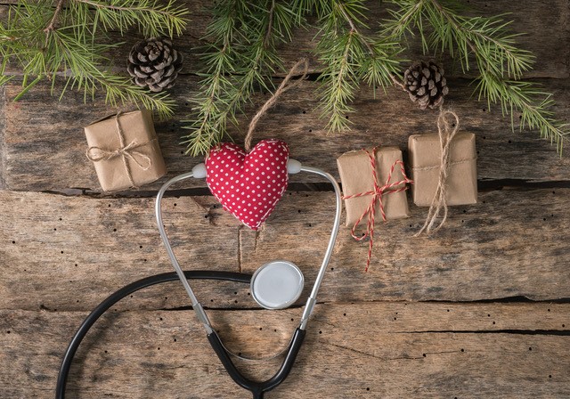 Heart Christmas ornament sitting on wood table with stethoscope and other ornaments around it